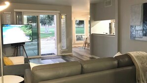 A modern living room with a large flat-screen TV, a leather sofa, and a dining area with a table and chairs. - +Guard Gated Golf Course Front 1mi to Vegas Strip, Quiet Secure best kept secret (Las Vegas)