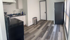 Eine kleine Küche mit Spüle, Schränken und einem schwarzen Kühlschrank.