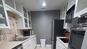 A modern kitchen with white cabinets, a stainless steel refrigerator, a microwave, and a dishwasher. - Cowboy Casa - DFW, AT&T Stadium, Stockyards (Hurst)