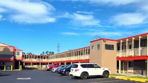 A motel with a row of parking spaces and a building with a red roof and beige walls. - Saratoga Motel By Capital O Near Midway Airport Chicago IL (Chicago)