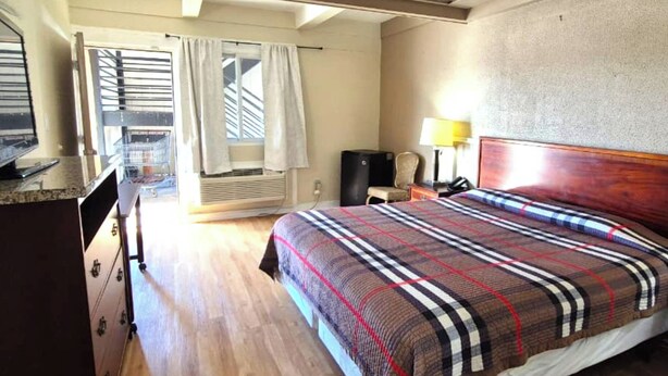 A hotel room with a bed, a desk, a chair, a lamp, and a window with curtains. - Saratoga Motel By Capital O Near Midway Airport Chicago IL (Chicago)
