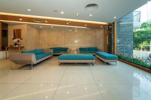 A modern hotel lobby with a seating area, a reception desk, and a large window providing a view of the outdoors. - Ocean Bliss Hotel (Da Nang)