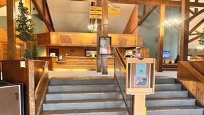 Eine Hotelhalle mit einer Rezeption, einer Holztreppe und einem Parkplatzschild.