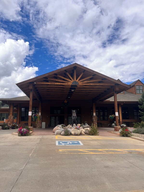 A building with a covered entrance, a bear statue, and a wheelchair-accessible parking space.