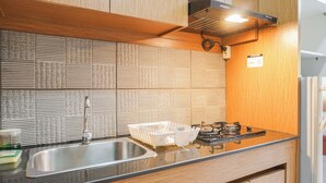 Una cocina con un lavamanos de acero inoxidable, armarios de madera, encimera negra y salpicadero texturizado.