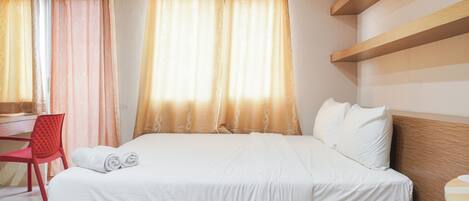 A bedroom with a bed, a desk, and a chair.