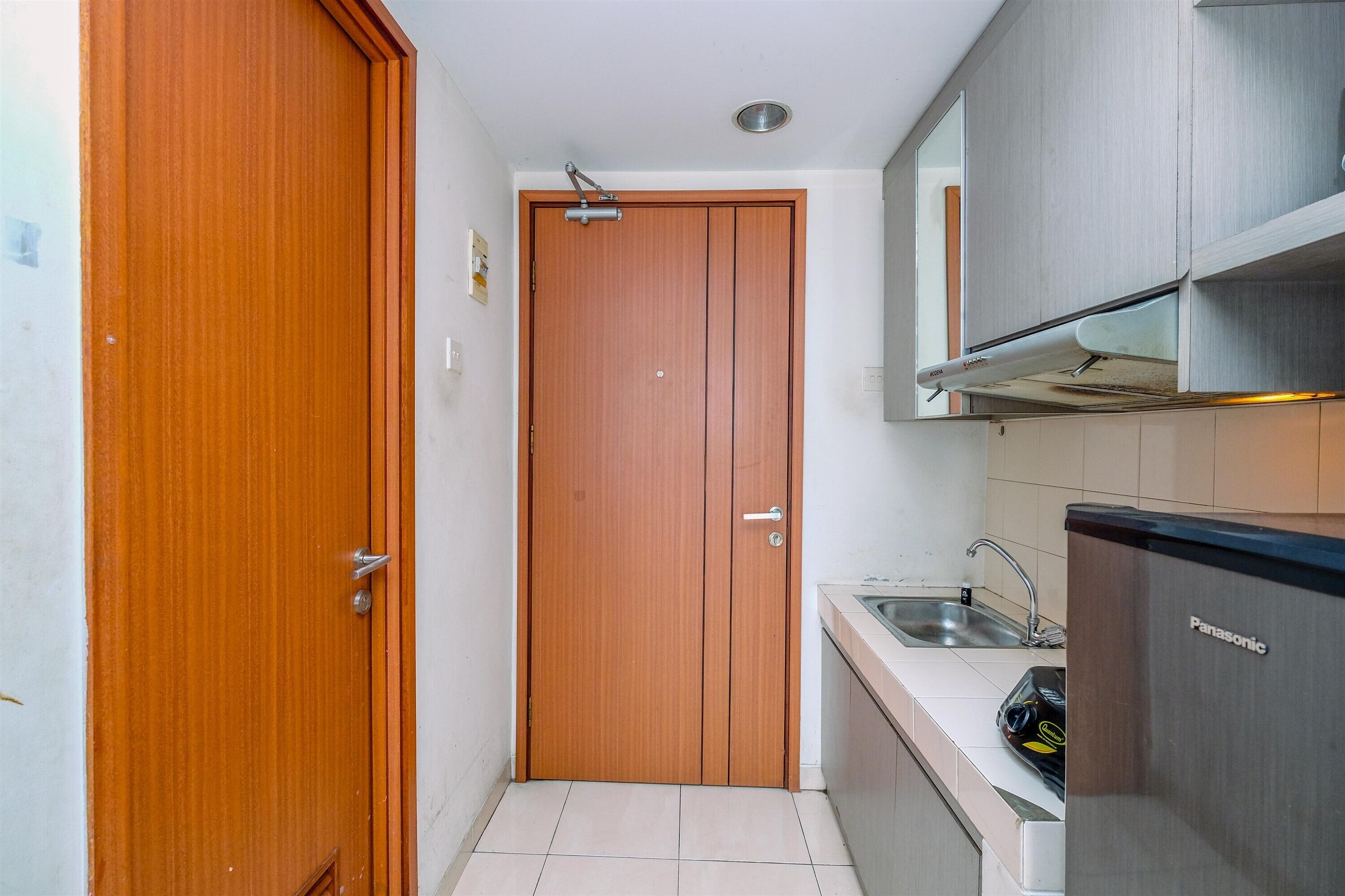 Eine kleine Küche mit Holztür, Spüle und Kühlschrank aus Edelstahl.