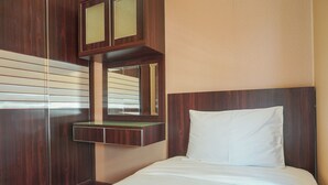 Una habitación de hotel con una cama grande, un armario de madera y un espejo sobre el mueble del lavabo.