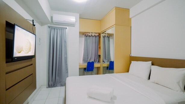 Een hotelkamer met een bed, een televisie, een spiegel en een kledingkast.