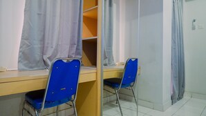 Een kamer met een bureau, twee blauwe stoelen, een spiegel en een garderobe.