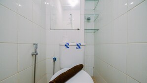 Een badkamer met witte betegelde wanden, een wit toilet, een douchegedeelte en een glazen plank boven het toilet.