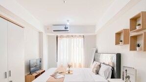 Een moderne slaapkamer met een bed, nachtkastje, televisie, airconditioning en een wandplank met planten.