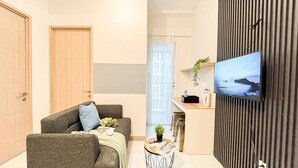 A modern living room with a sofa, a coffee table, and a TV mounted on a wall. - Scandinavian Touch With 2Br At Tokyo Riverside Pik 2 Apartment (Teluknaga)