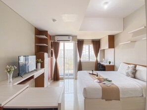 Een moderne hotelkamer met een bed, een bureau, een televisie en een raam met gordijnen.