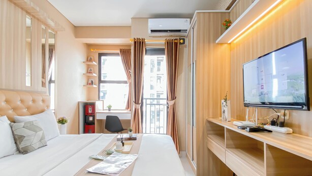 Quarto de hotel moderno com uma cama grande, uma escrivaninha, uma televisão e uma janela com cortinas.