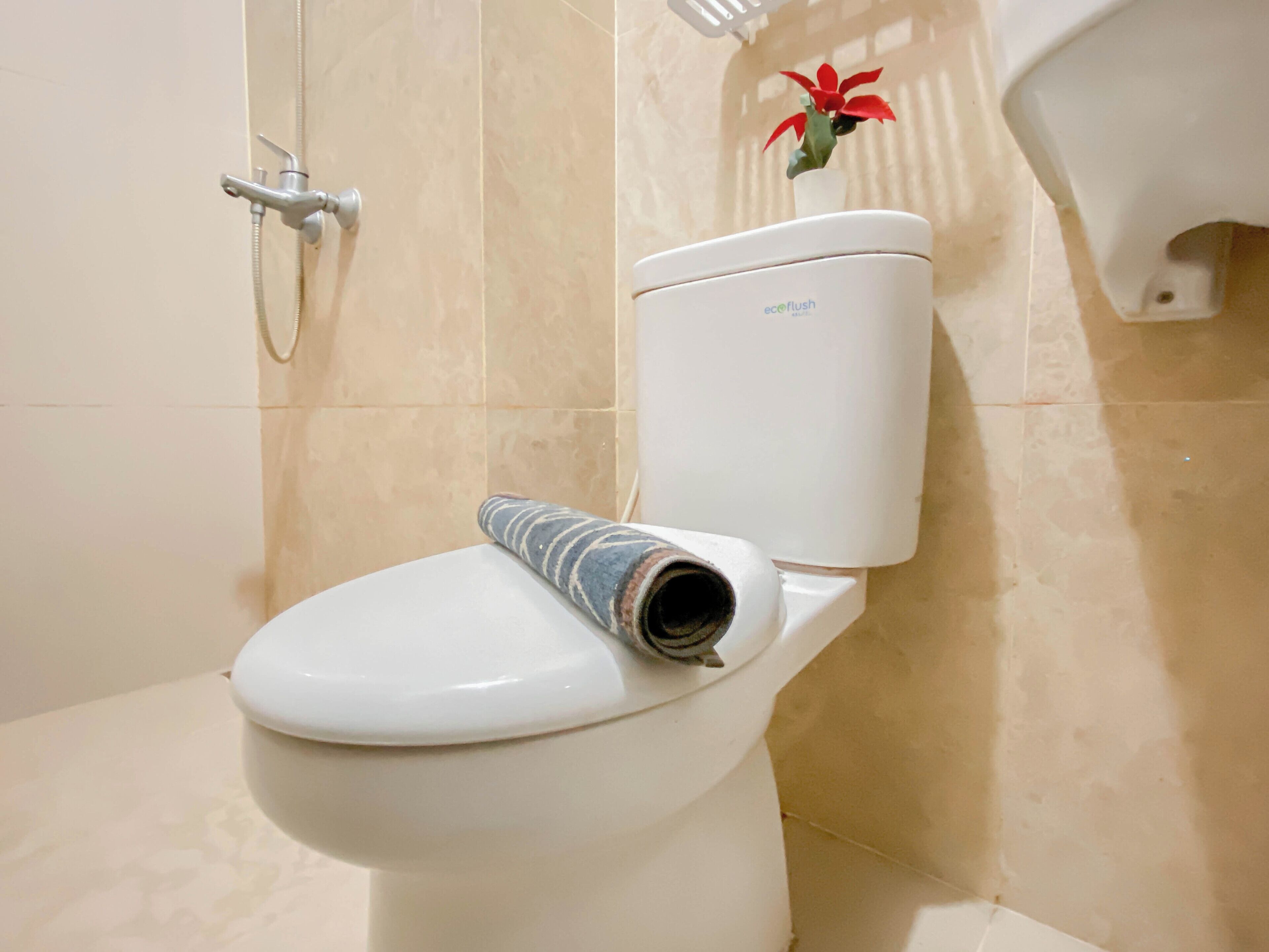 Des toilettes avec un porte-rouleau de papier toilette et une fontaine à eau en arrière-plan.