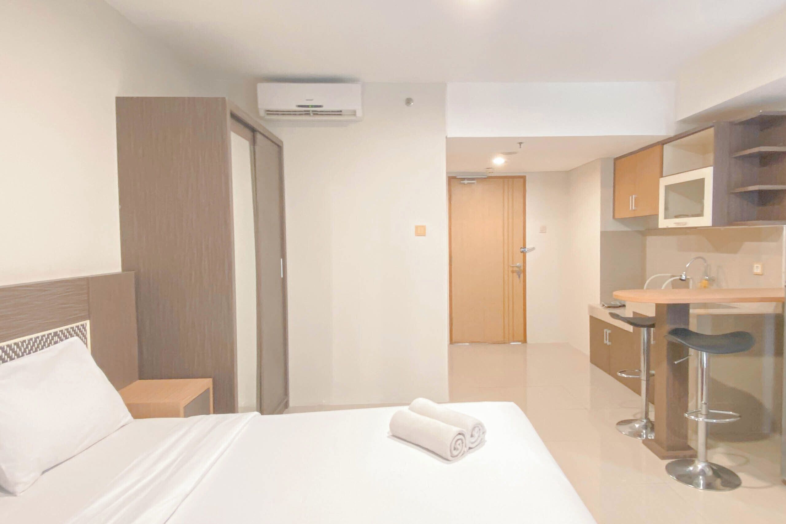 Una habitación de hotel con cama, una mesita, baño y kitchenette.