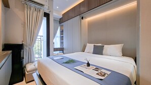 Una habitación de hotel moderna con una cama grande, un escritorio y un ventanal con cortinas.