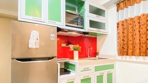 A kitchen with a refrigerator, a sink, and a microwave. - Simple 2Br Near Industrial Area Apartment Meikarta (Cikarang)
