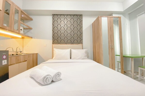 A hotel room with a bed, a desk, a wardrobe, and a mirror. - Basic Studio At Candiland Apartment (Semarang)