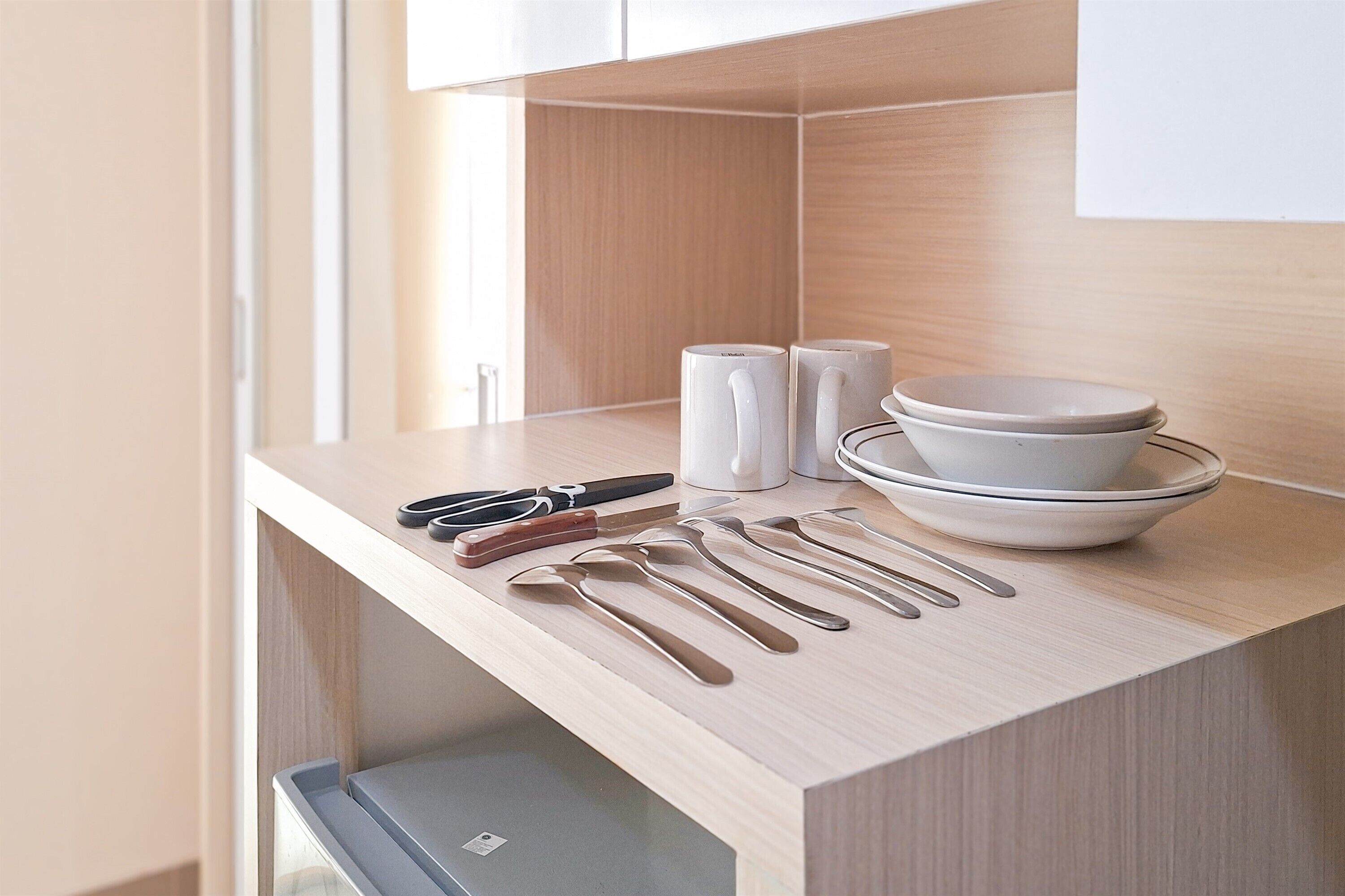 A kitchen counter with utensils, salt and pepper shakers, and stacked bowls.