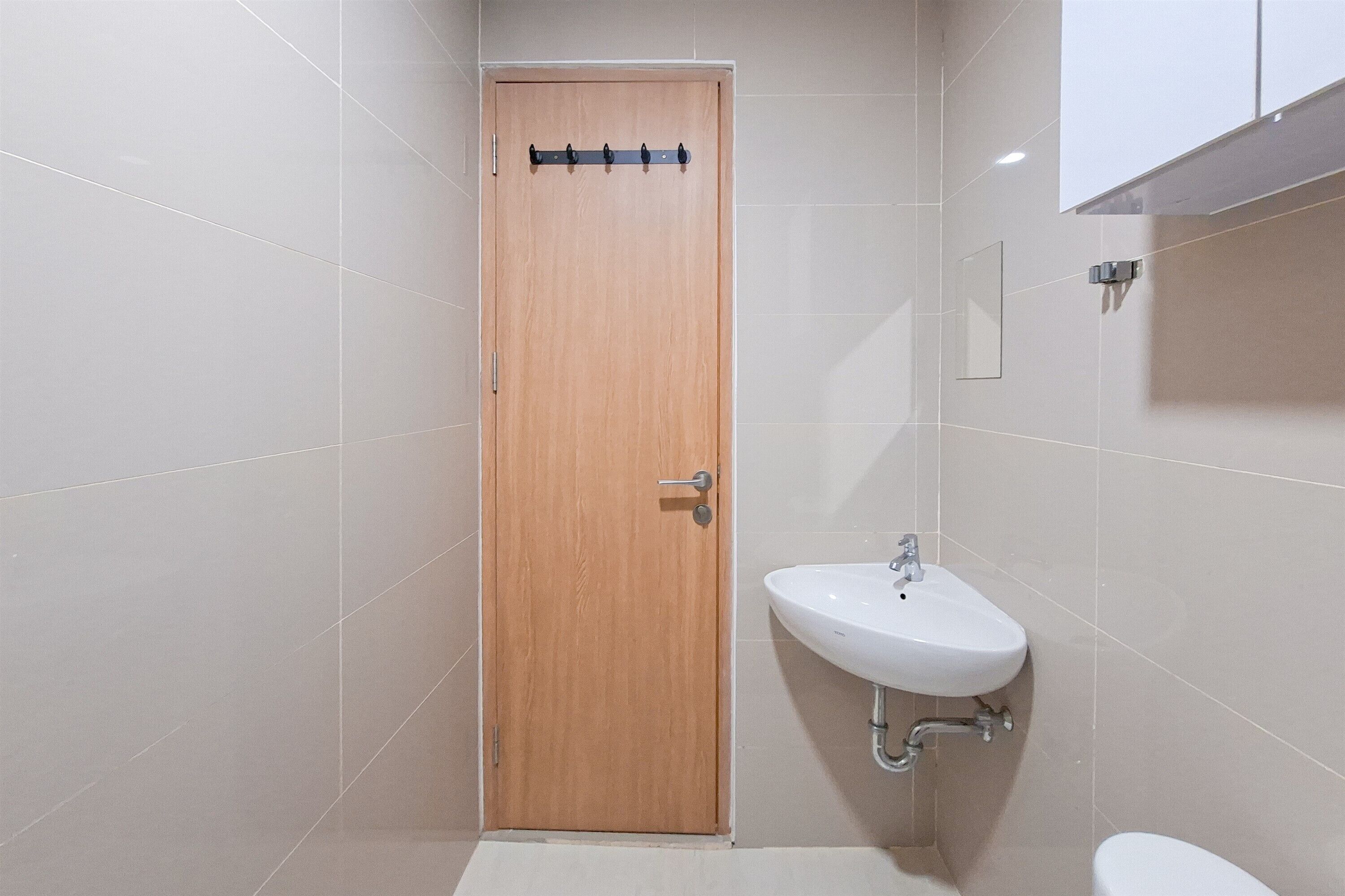 Une salle de bain avec une porte en bois, un lavabo blanc et des toilettes.