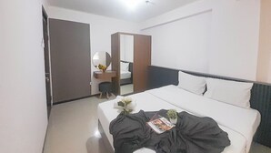 Et hotelværelse med en seng, et natbord, et spejl og en dør.