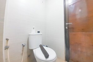 Un baño con un inodoro blanco, un dispensador de papel higiénico y una palanca para la descarga.