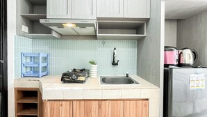A compact kitchen with a sink, a stove, and a refrigerator. - Simple Space Studio At Belmont Residence Puri Apartment (Jakarta)