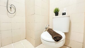 Un baño con inodoro, ducha y una pequeña planta en maceta en la pared.