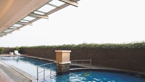 A swimming pool with a stone wall and a glass ceiling structure. - Simple Space Studio At Belmont Residence Puri Apartment (Jakarta)