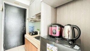 A compact kitchenette with a black door, a sink, and two electric kettles on a countertop. - Simple Space Studio At Belmont Residence Puri Apartment (Jakarta)