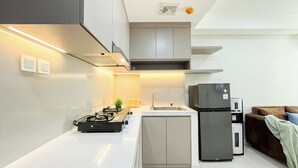 A modern kitchen with a gas stove, sink, and black refrigerator. - Serene Stay 2Br At Daan Mogot City Apartment (Jakarta)
