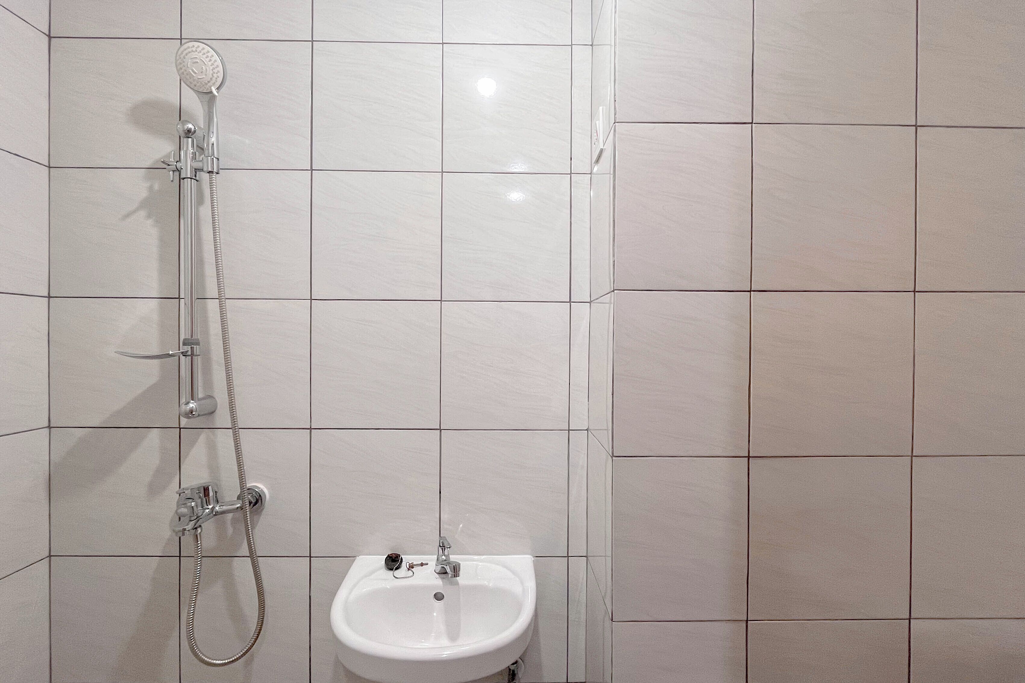 A bathroom with a shower, a sink, and tiled walls.