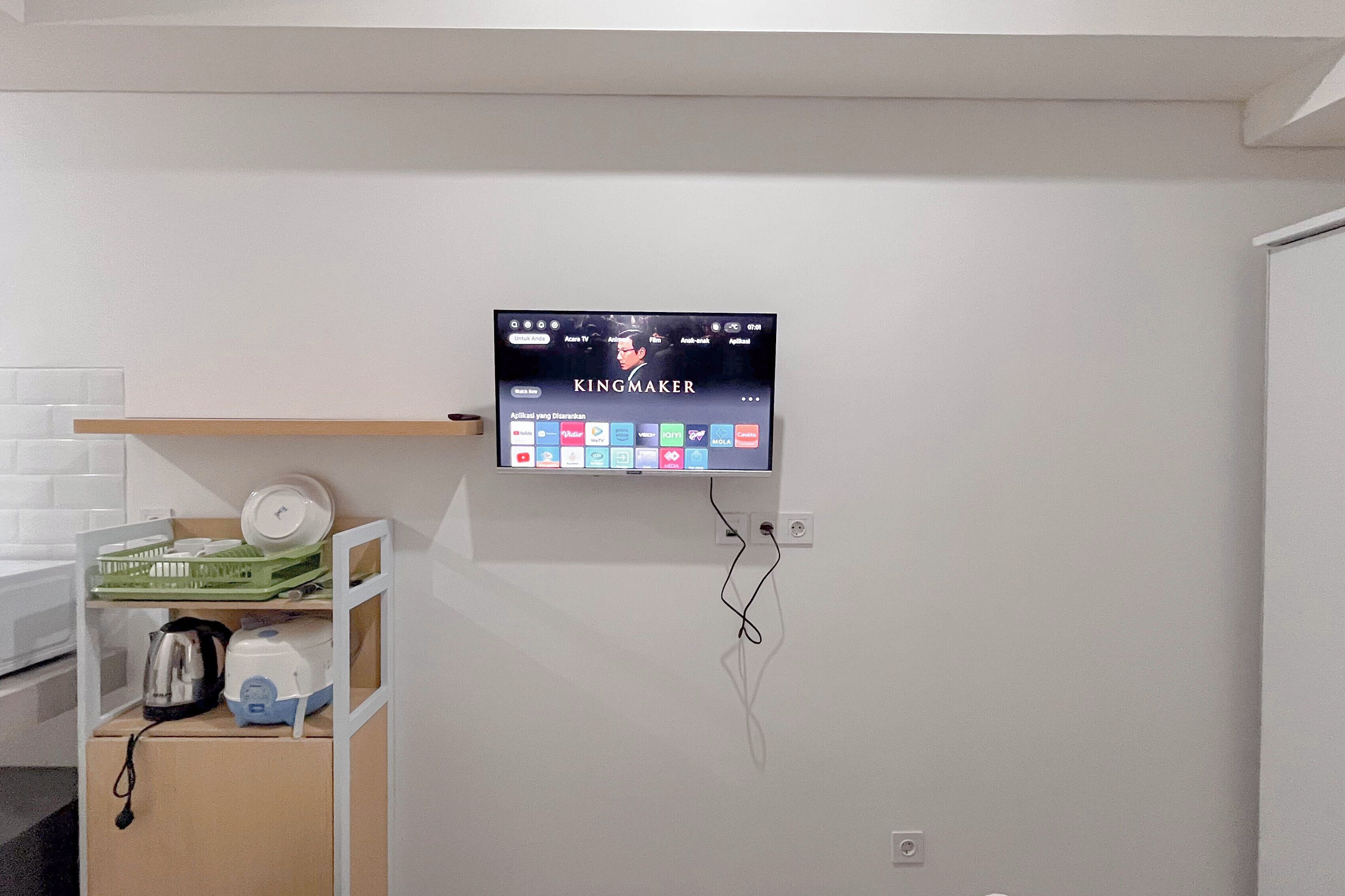 A television mounted on a wall displaying the movie 'KINGMAKER' with various streaming service icons below.