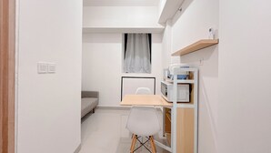 A compact kitchen with a dining table, a microwave, and a small cabinet.