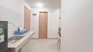 A modern kitchen with a white countertop, a sink, and a wooden door.