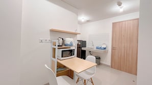 A compact kitchen with a microwave, sink, and wooden cabinet.