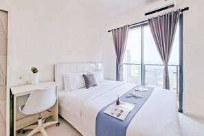 A modern hotel room with a large bed, a desk, and a view of the city. - Studio Apartment Near Aeon Mall At Sky House Bsd (Pagedangan)