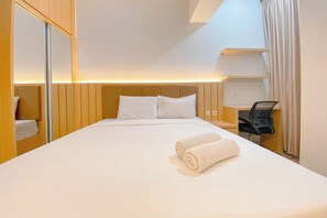 A hotel room with a large bed, a desk, and a chair. - Wooden Nest Studio At The Alton Apartment (Semarang)