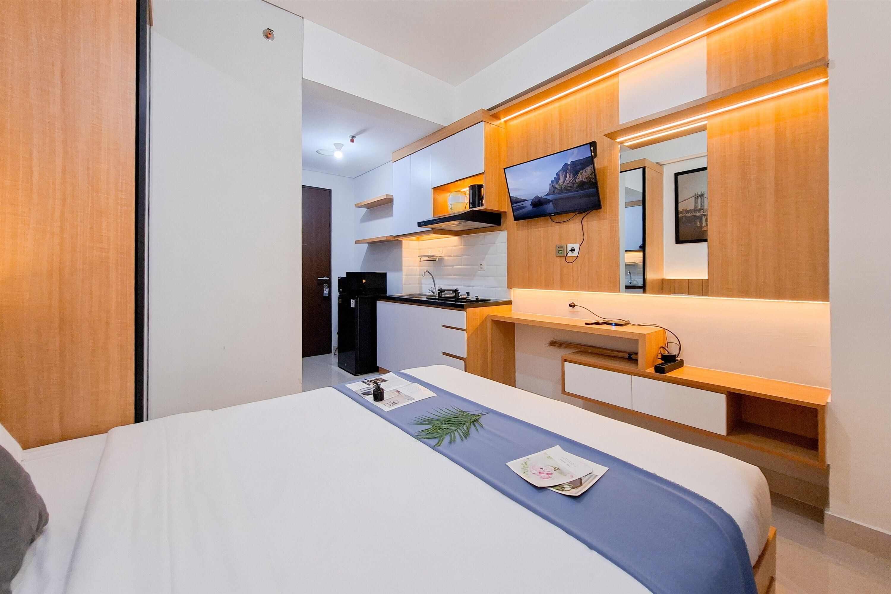 Une chambre d’hôtel moderne équipée d’un lit, d’un bureau, d’une télévision et d’une kitchenette.