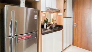 A modern kitchen with stainless steel appliances, white cabinetry, and a wooden door. - Scandinavian Modern Studio Apartment At Springhill Terrace Residence (Jakarta)