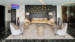 A modern lobby with a sofa set, two armchairs, a coffee table, and a wall-mounted TV. - 2Br With Private Lift Near Station At Menteng Park Apartment (Jakarta)