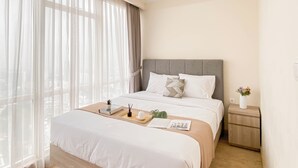 A neatly arranged hotel room with a large bed, a bedside table with a vase, and a view through sheer curtains. - 2Br With Private Lift Near Station At Menteng Park Apartment (Jakarta)