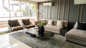 A modern living room with a sofa, two armchairs, a coffee table, and a potted plant. - Modern Studio Near Ambarrukmo Plaza At Barsa City Apartment (Yogyakarta)
