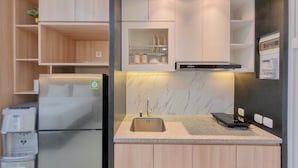 A compact kitchen with a built-in refrigerator, a sink, and a microwave. - Modern Studio Near Ambarrukmo Plaza At Barsa City Apartment (Yogyakarta)