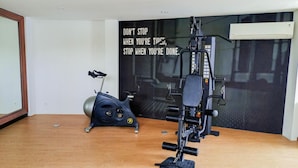 A home gym with a stationary bike and a multi-functional exercise machine. - Modern Studio Near Ambarrukmo Plaza At Barsa City Apartment (Yogyakarta)