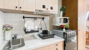 A compact kitchen with a stainless steel sink, a microwave, and a small stove. There are wooden cabinets and a white countertop. - Studio with View at Royal Sentul Park (Bogor)
