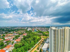 A high-rise building with multiple floors and balconies, surrounded by a densely populated urban area with various buildings and greenery. - 2Br Near Mall At Cinere Bellevue Suites Apartment (Depok)