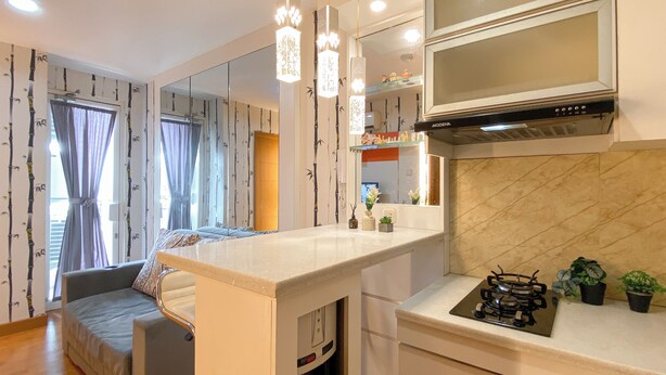 A modern kitchen with a built-in microwave, a stove, and a large mirror above the counter. - 2Br Near Mall At Cinere Bellevue Suites Apartment (Depok)